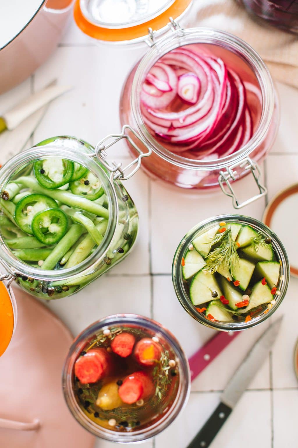 pickled green beans, red onions, carrots and cucumbers in open glass jars