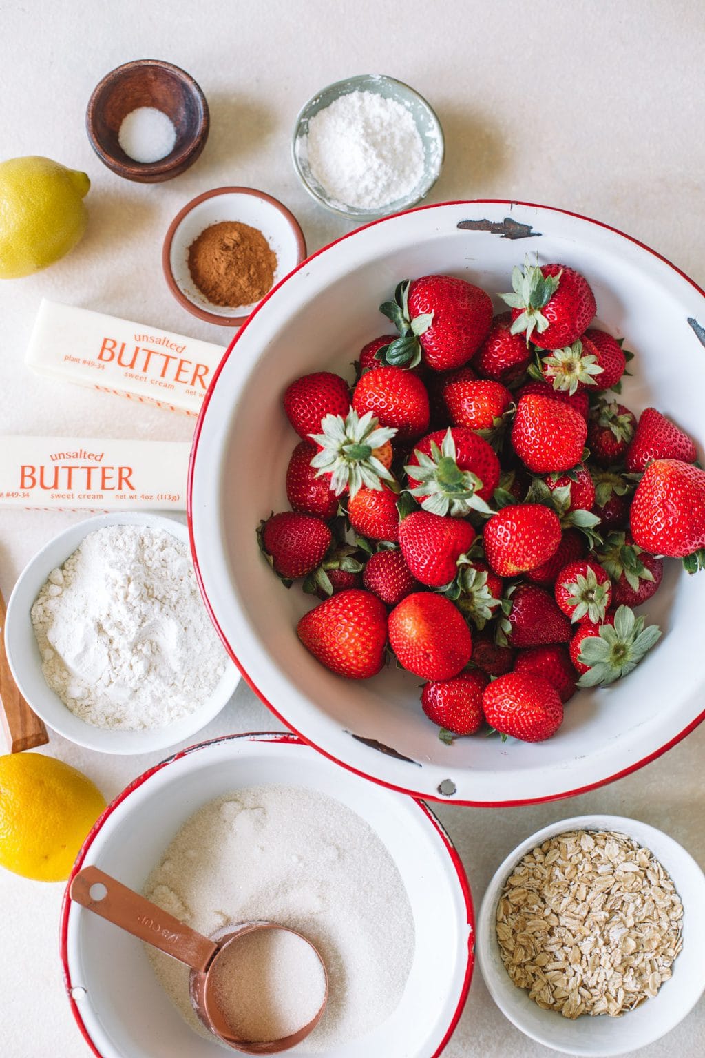 fresh strawberries in white bowl, butter sticks, cinnamon, sugar, flour, cornstarch, oats, lemon