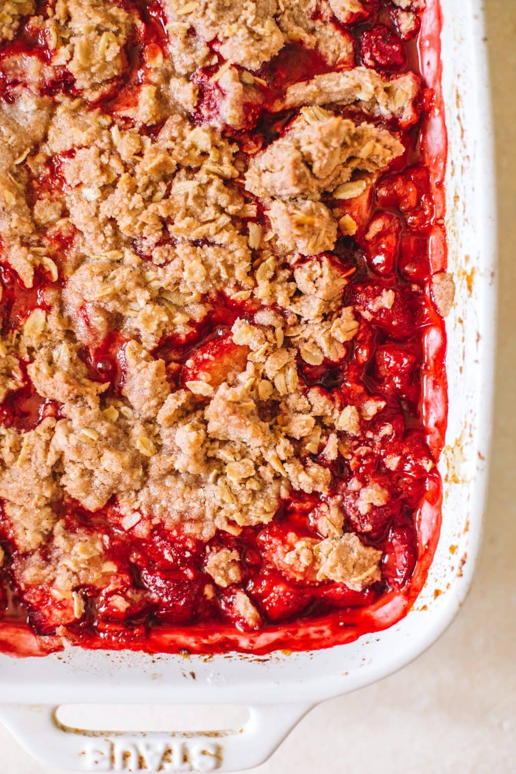 close-up of warm, bubbly strawberry crisp in white casserole dish