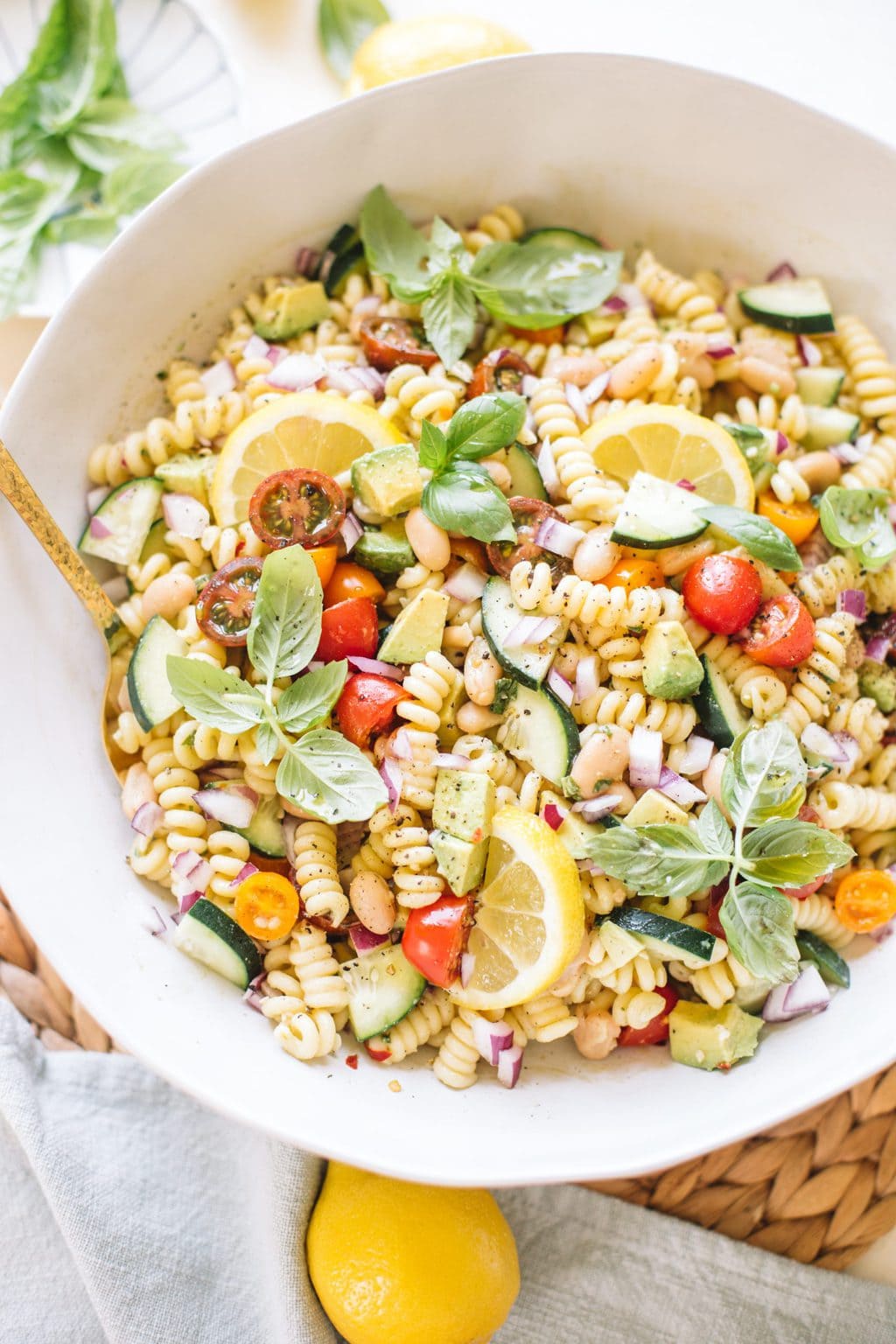 easy pasta salad with beans, avocado, cucumbers, tomatoes, basil in white bowl