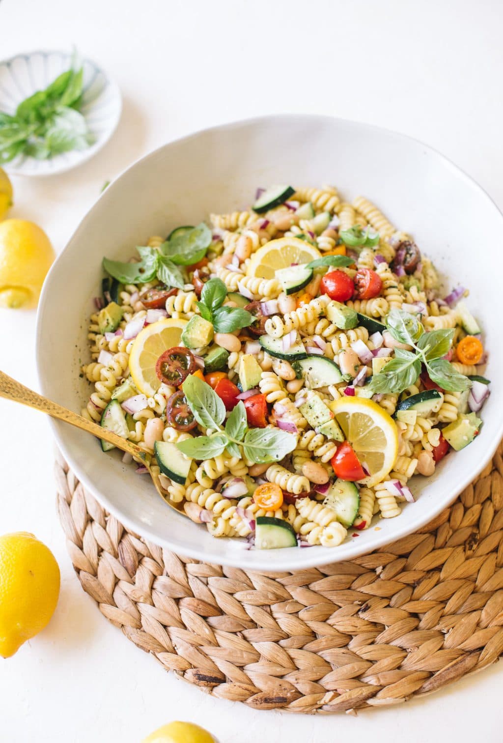 vegan pasta salad with cucumbers, tomatoes, basil in white bowl