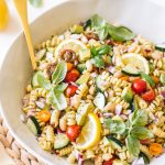 vegan pasta salad with cucumbers, tomatoes, basil in white bowl