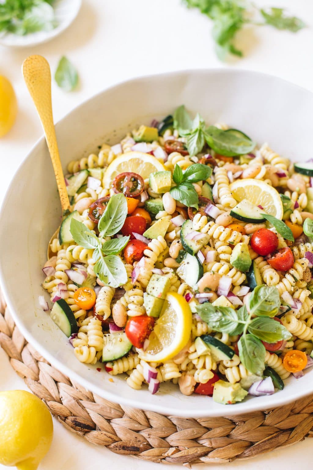 vegan pasta salad with cucumbers, tomatoes, basil in white bowl