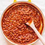 vegetarian baked beans in yellow dutch oven with wooden spoon