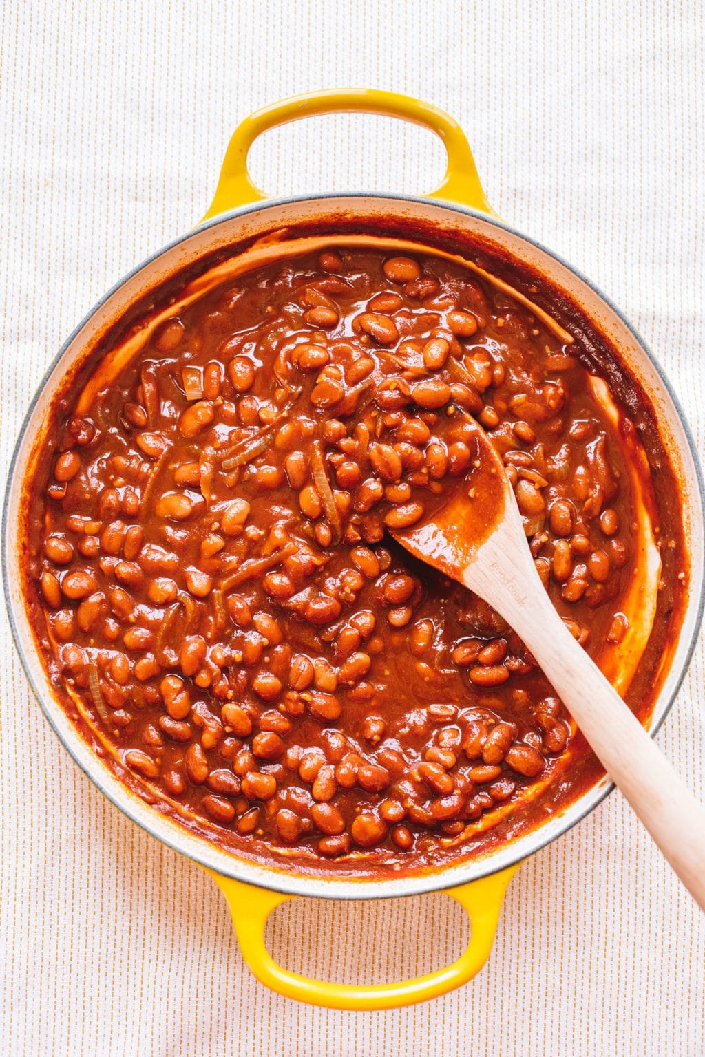 vegetarian baked beans in yellow dutch oven with wooden spoon