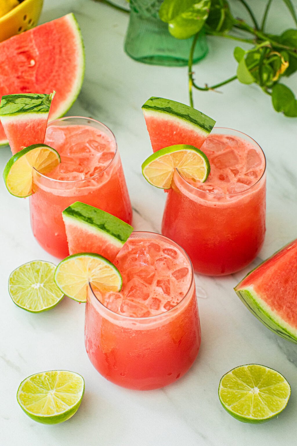 three glasses filled with watermelon vodka cocktail and topped with lime wheels and watermelon wedges