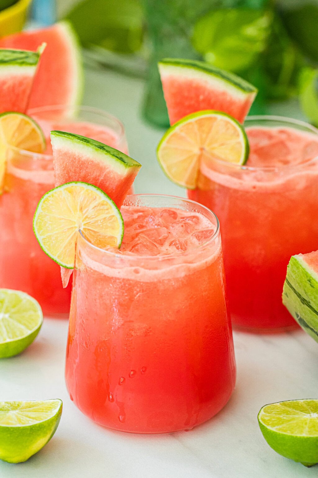 a cocktail glass filled with watermelon vodka cocktail and garnished with a fresh watermelon wedge and a lime wheel