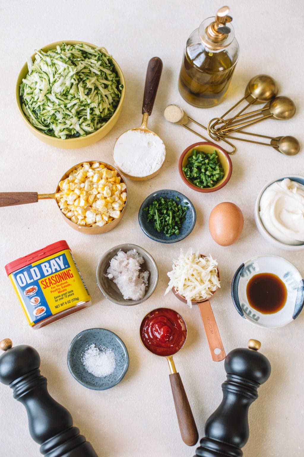 shredded zucchini, corn kernels, old bay seasoning, parm cheese, salt, pepper, garlic powder, jalapeno, chives, eggs, ketchup, mayo, measuring cups and teaspoons