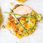 summer zucchini and corn fritters topped with creamy sauce and chives