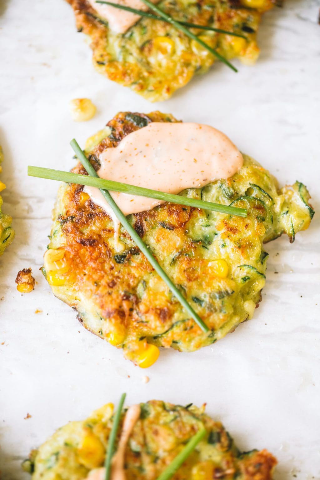 summer zucchini and corn fritters topped with creamy sauce and chives