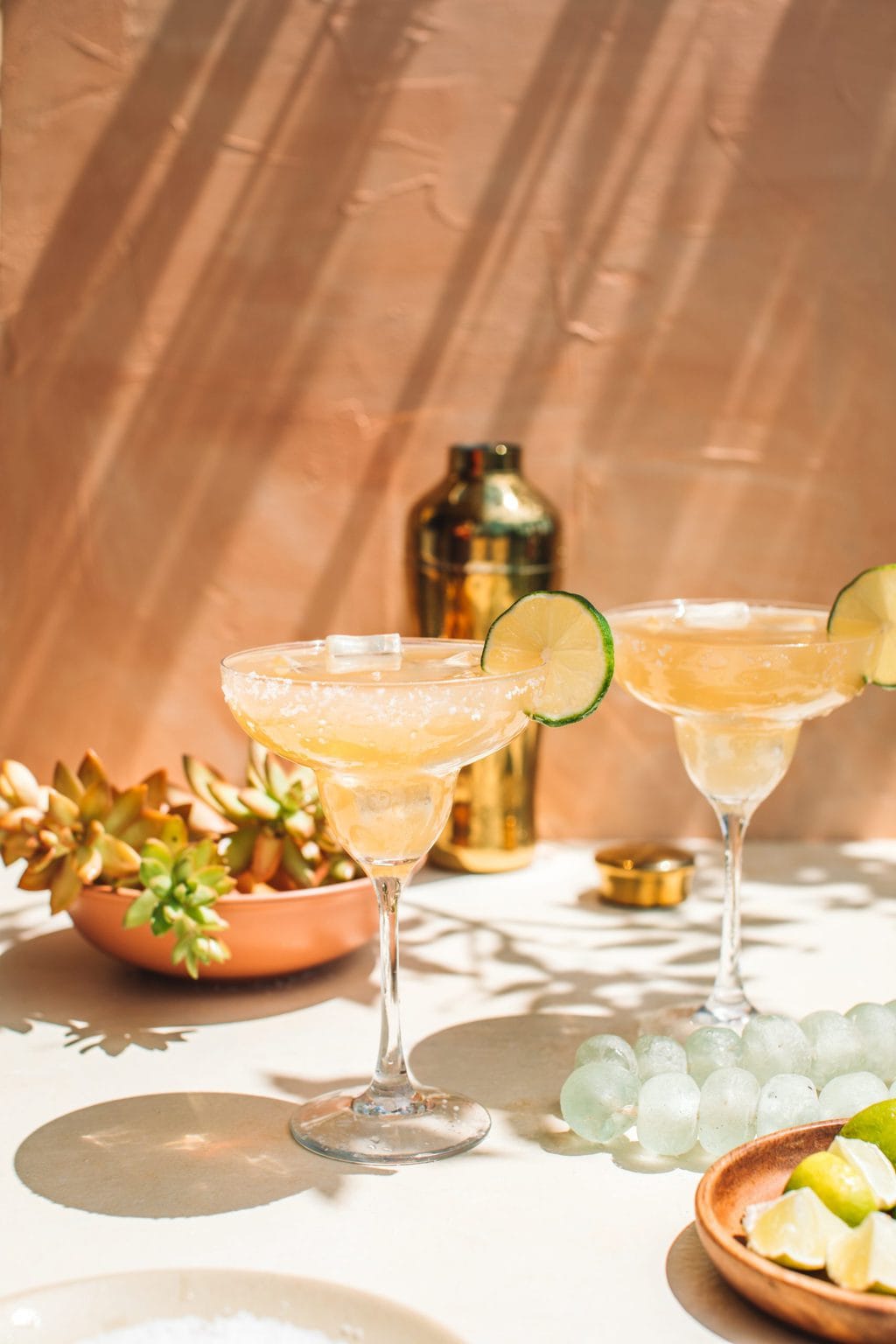 two top-shelf tequila margaritas in glasses with cocktail shaker