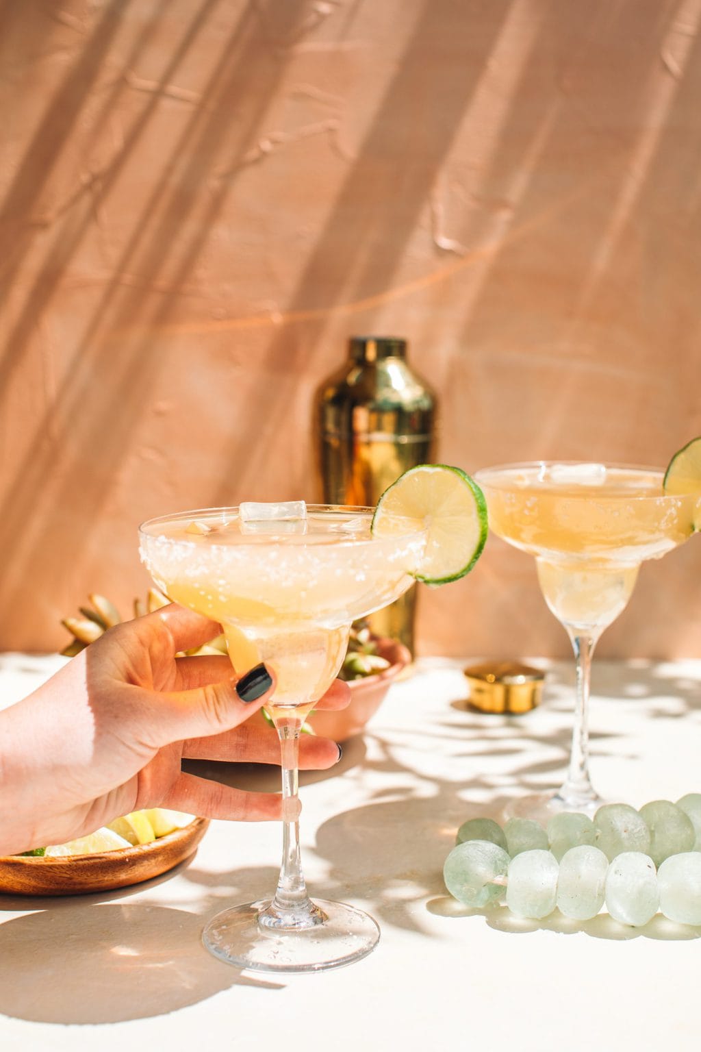 hand holding cadillac margarita in chilled glass with second margarita on side