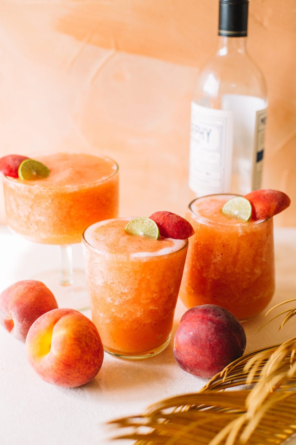 frozen peach strawberry white wine slushies in glasses with peach garnish