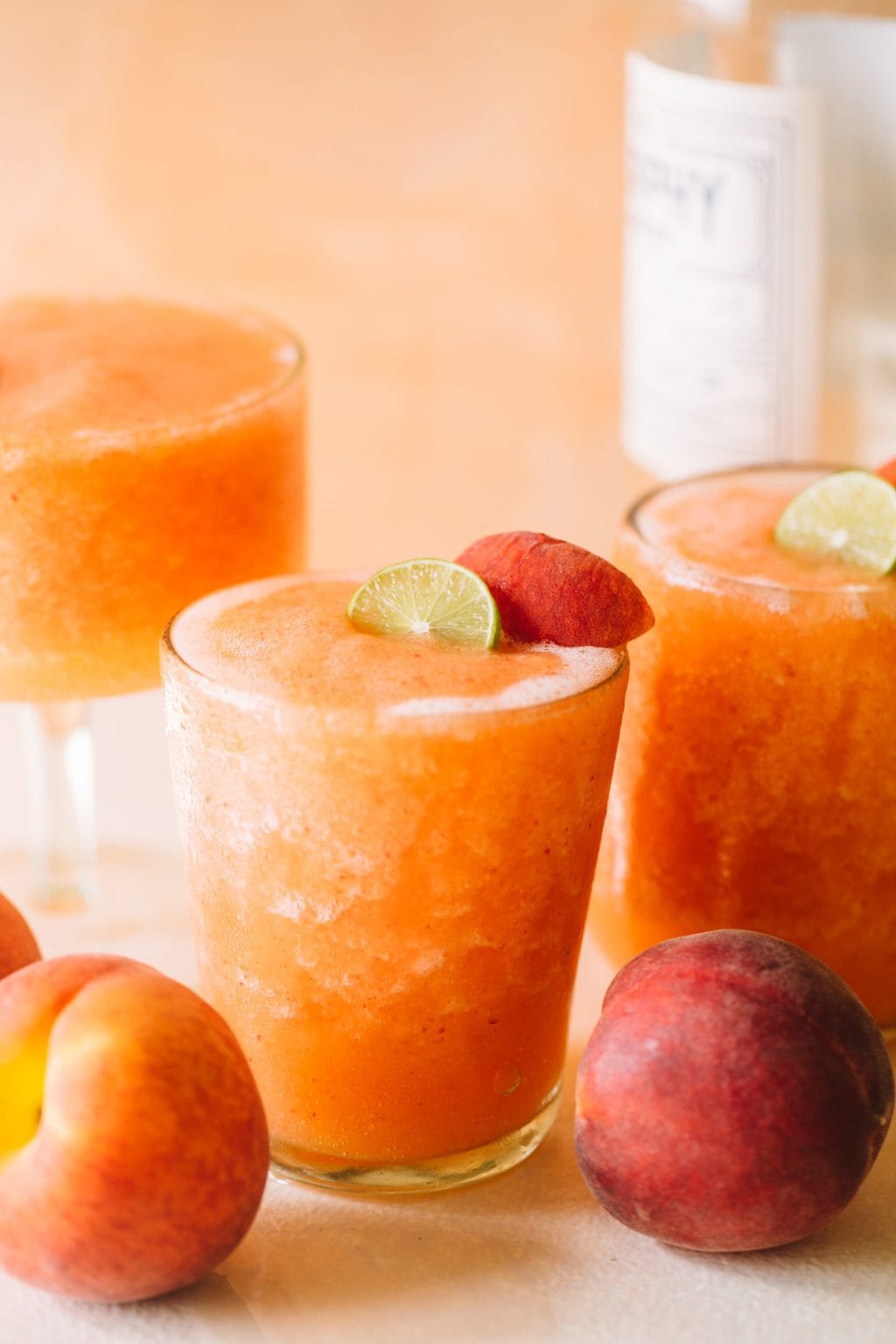 frozen peach white wine slushies in glasses with peach garnish