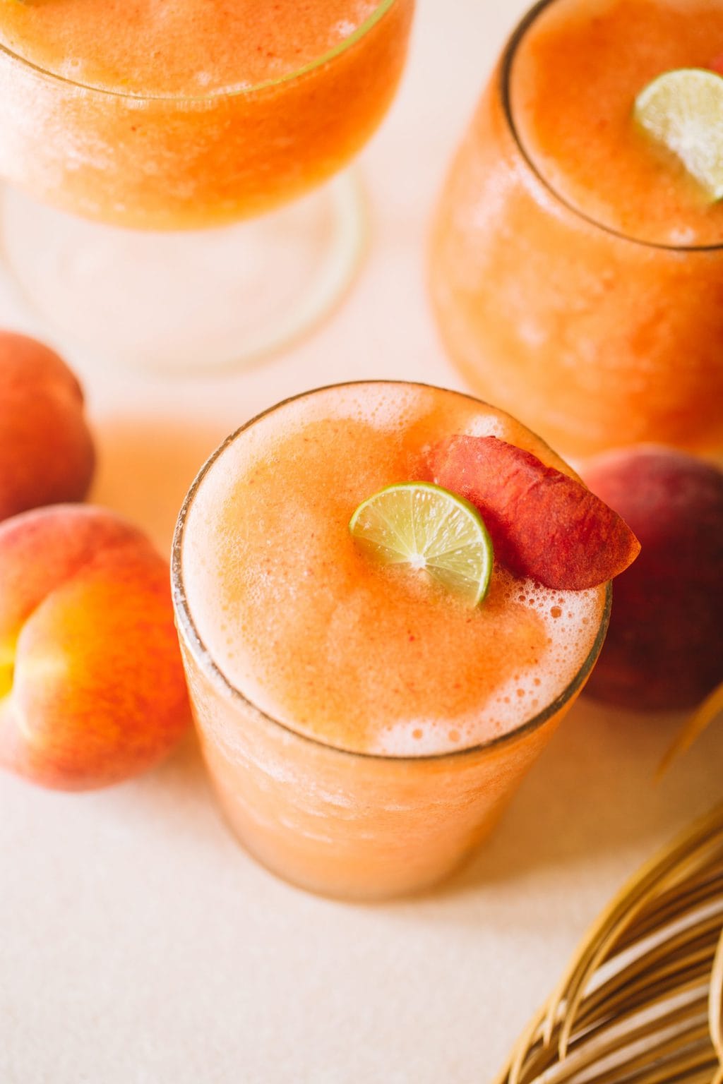 easy frozen peach cocktail recipe in glass with peach garnish