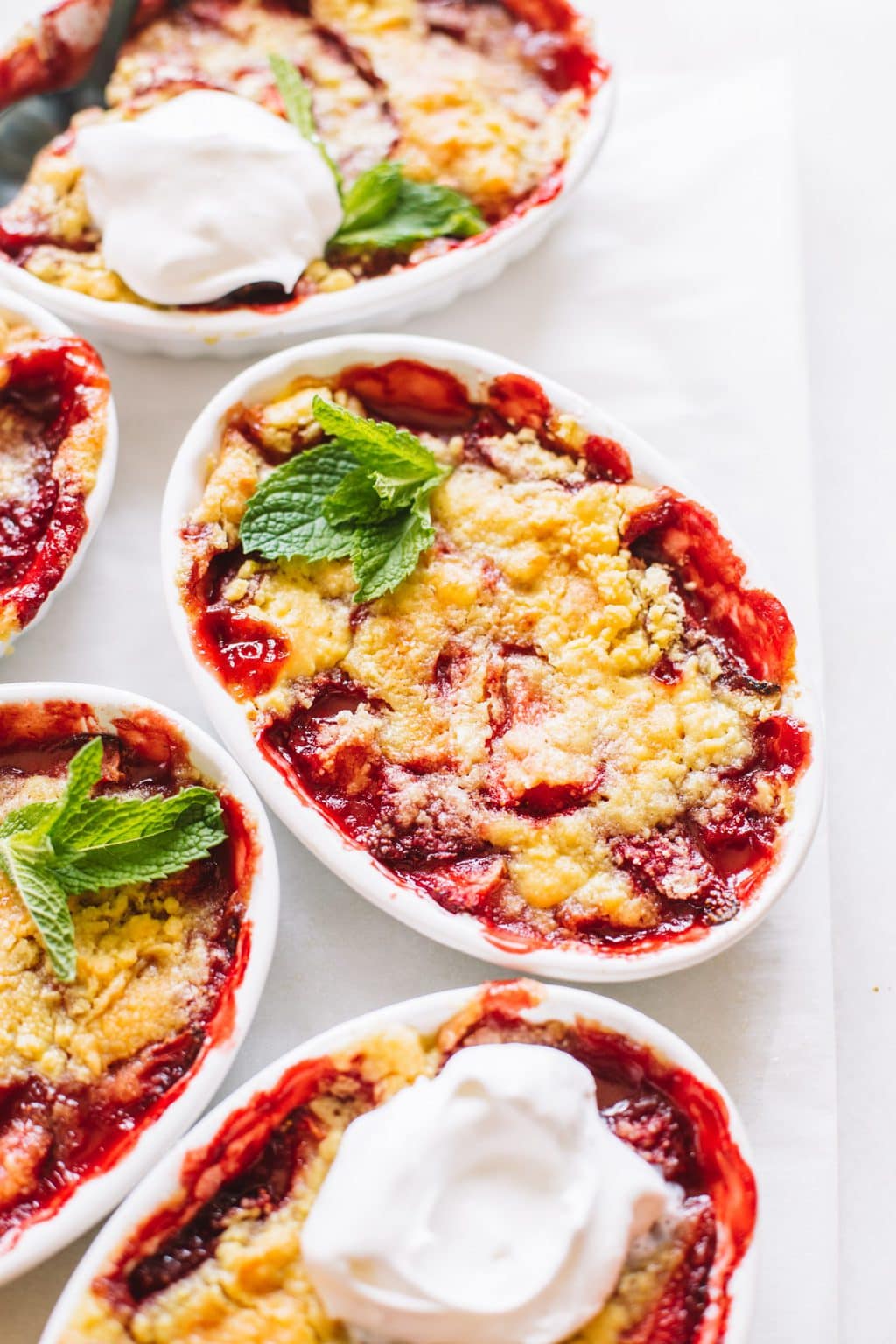 Baked strawberry dump cake in a small ramekin topped with whip cream and mint leaves.