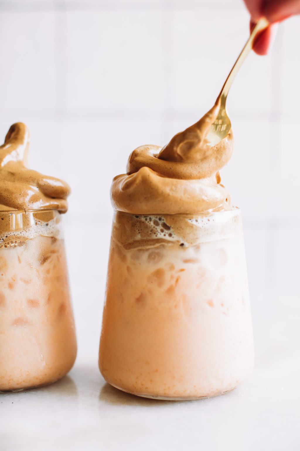 A glass filled with milk being topped with whipped coffee. 