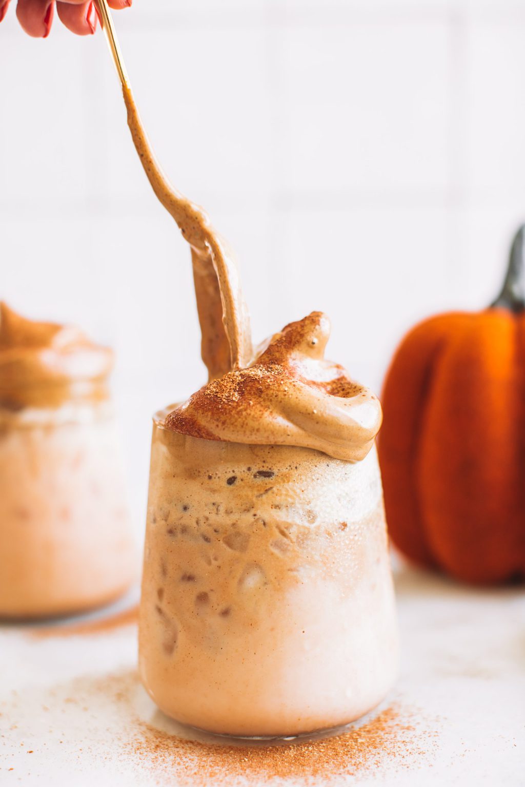 Glass filled with pumpkin milk topped with whipped coffee. 