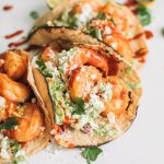 easy shrimp taco recipe with cilantro lime slaw in charred corn tortillas on white surface