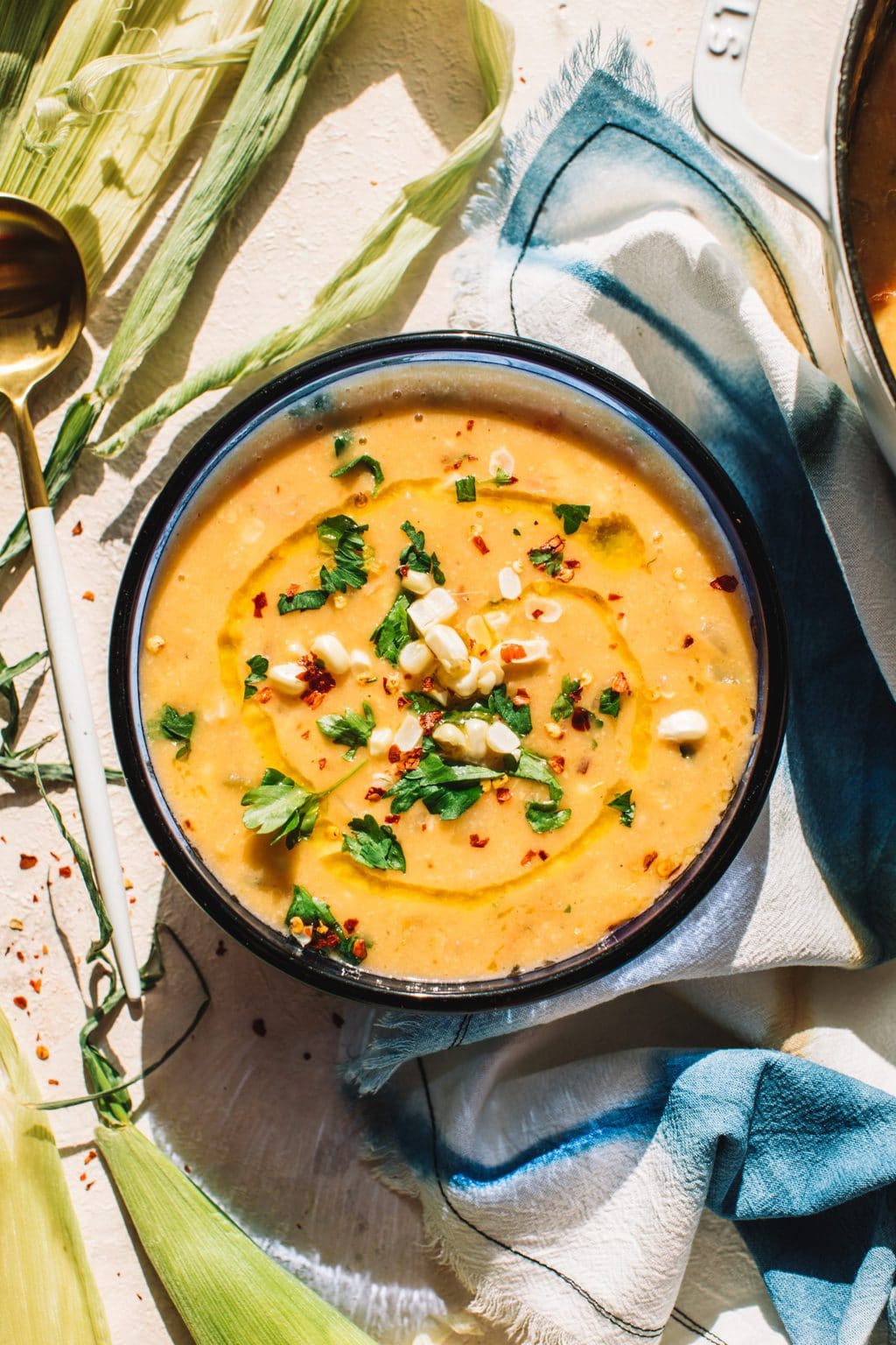 easy corn soup recipe in blue bowl garnished with fresh corn, chives and parsley