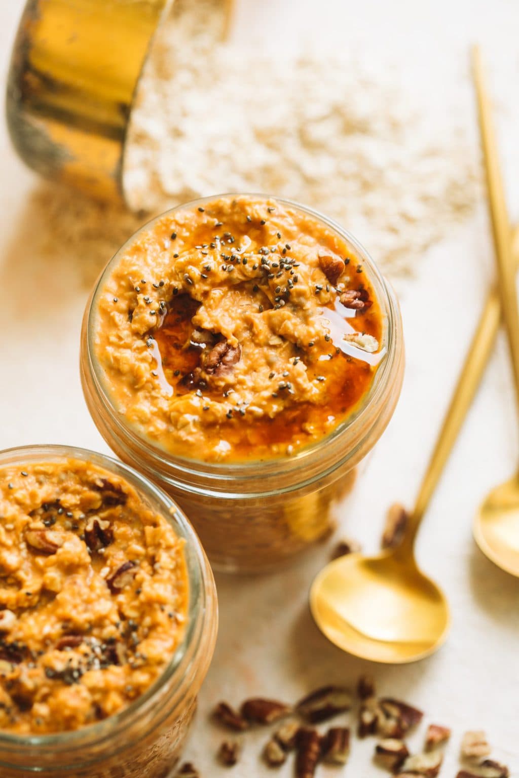 two small mason jars of pumpkin overnight oats with oats and gold spoon