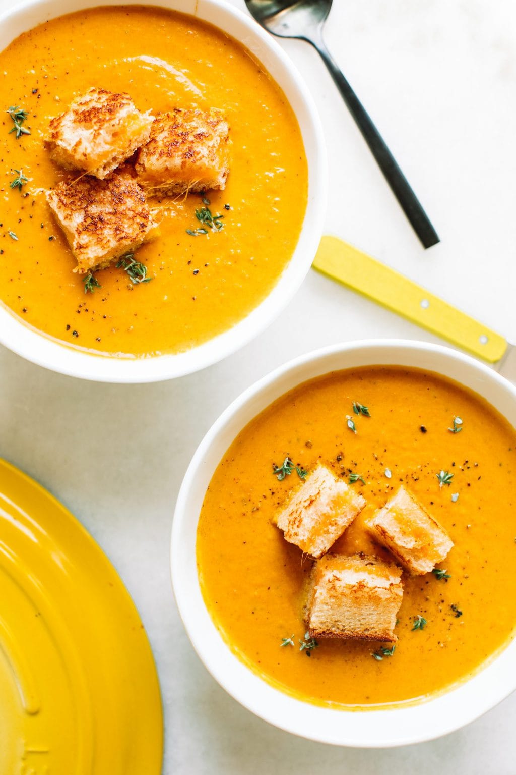 creamy pumpkin soup recipe in two white bowls with grilled cheese croutons