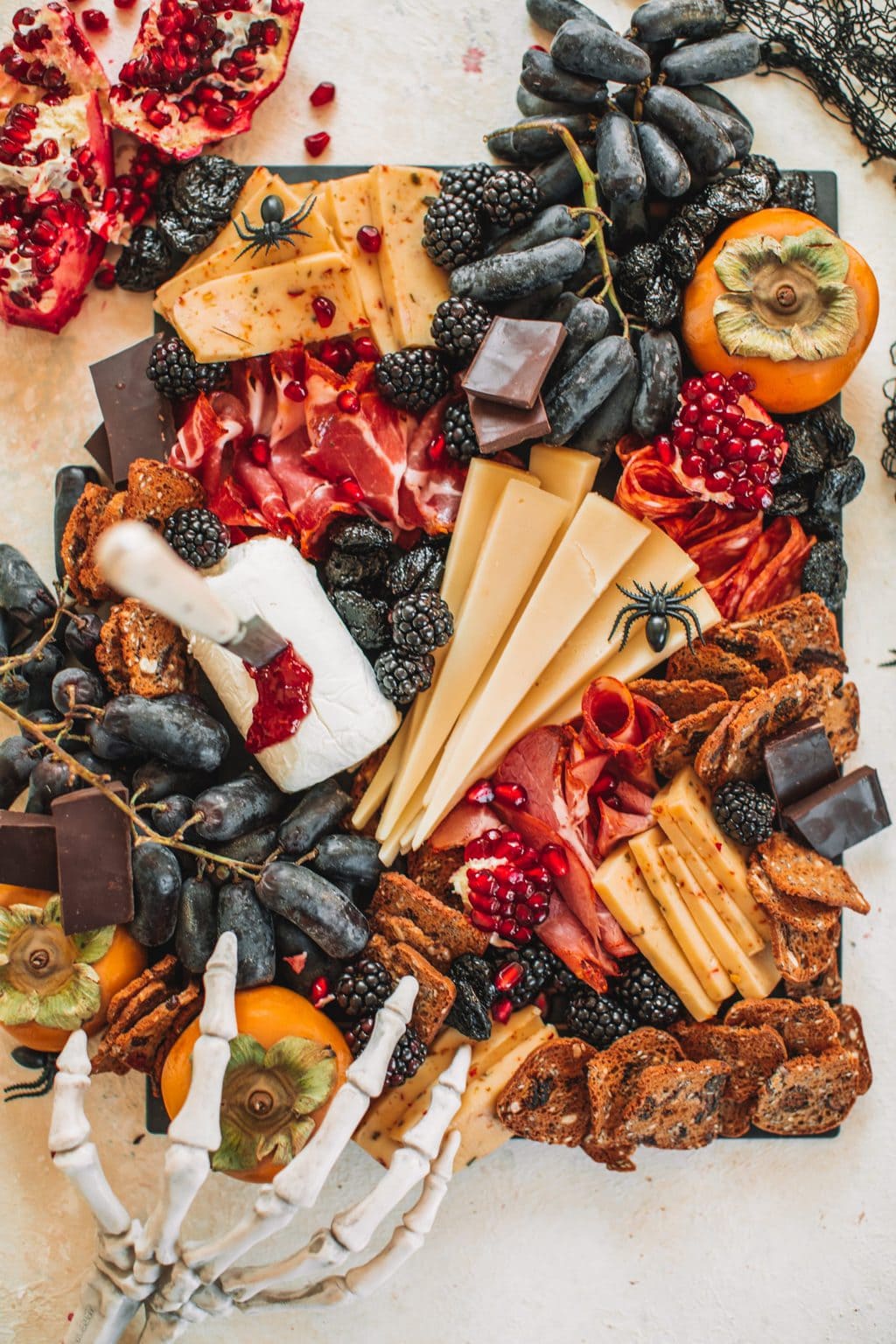 A spooky cheeseboard with cheeses, fruits, crackers and nuts.