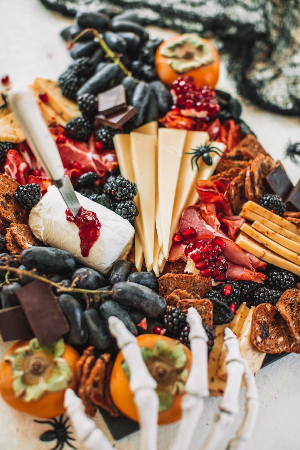 A spooky cheeseboard with cheeses, fruits, crackers and nuts. 