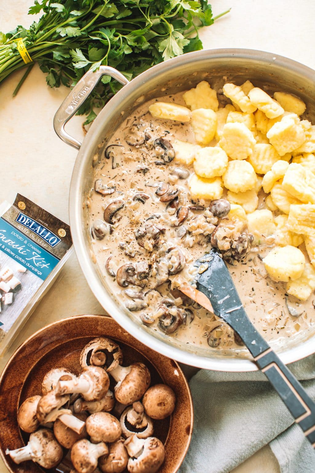 Mushrooms and gnocchi in a cream sauce garnished with parsley in a skillet.