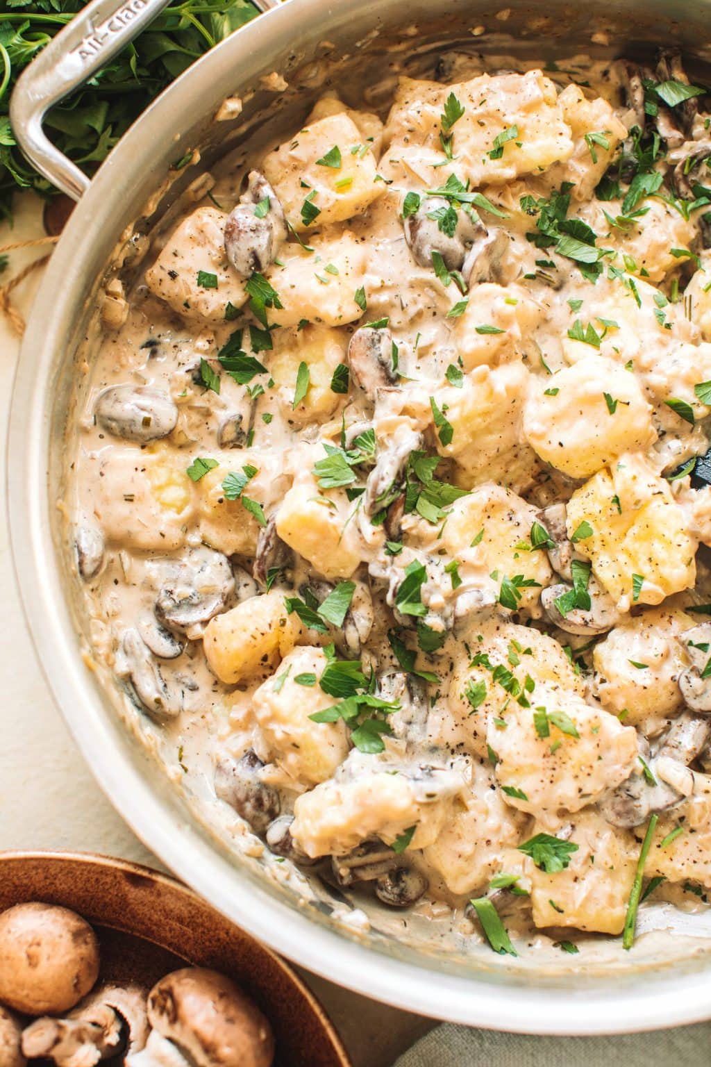 Mushrooms and gnocchi in a cream sauce garnished with parsley in a skillet.