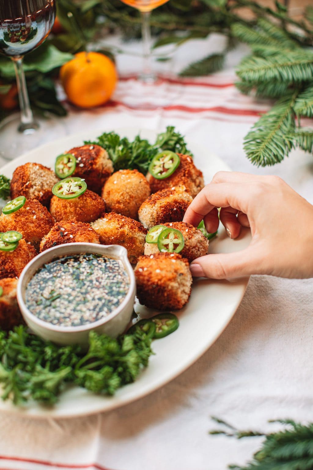 Spicy tuna croquette being pulled off a white serving platter.