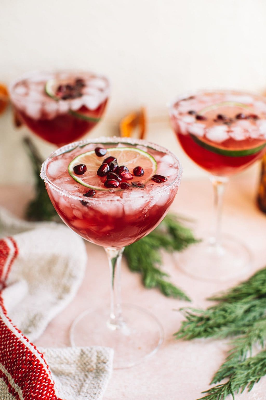 Cocktail glass filled with pomegranate christmas margarita on holiday tablescape