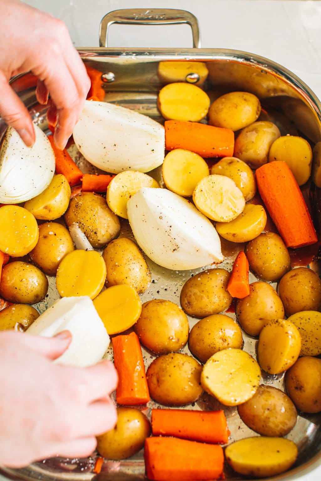 Small Yukon potatoes, chopped carrots, and quartered onions arranged in a roasting dish