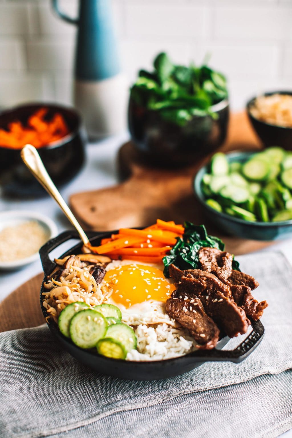 top shot of bibimbap bowl topped with sliced meat, egg, carrots, and other veggies