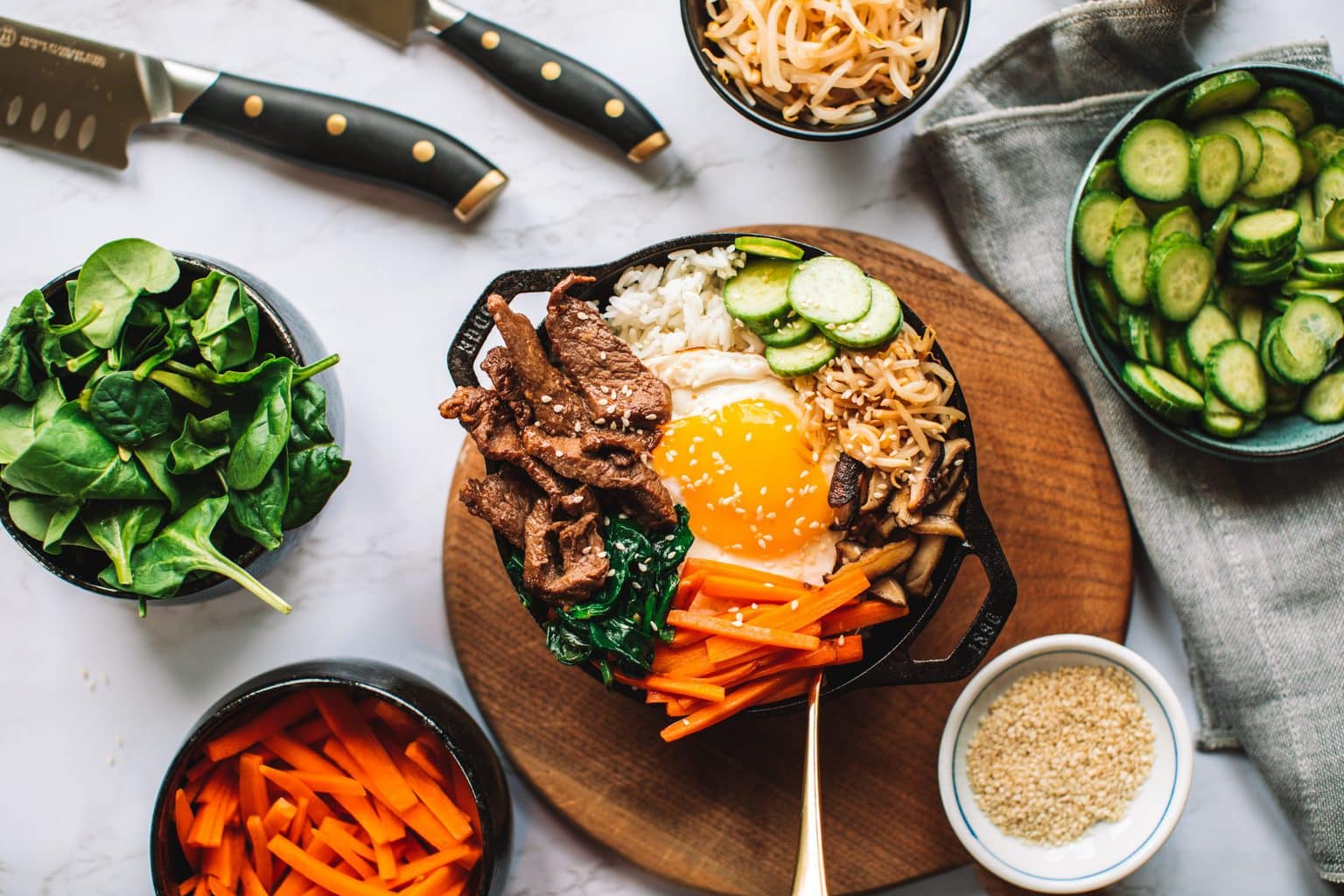 top shot of bibimbap bowl topped with sliced meat, egg, carrots, and other veggies