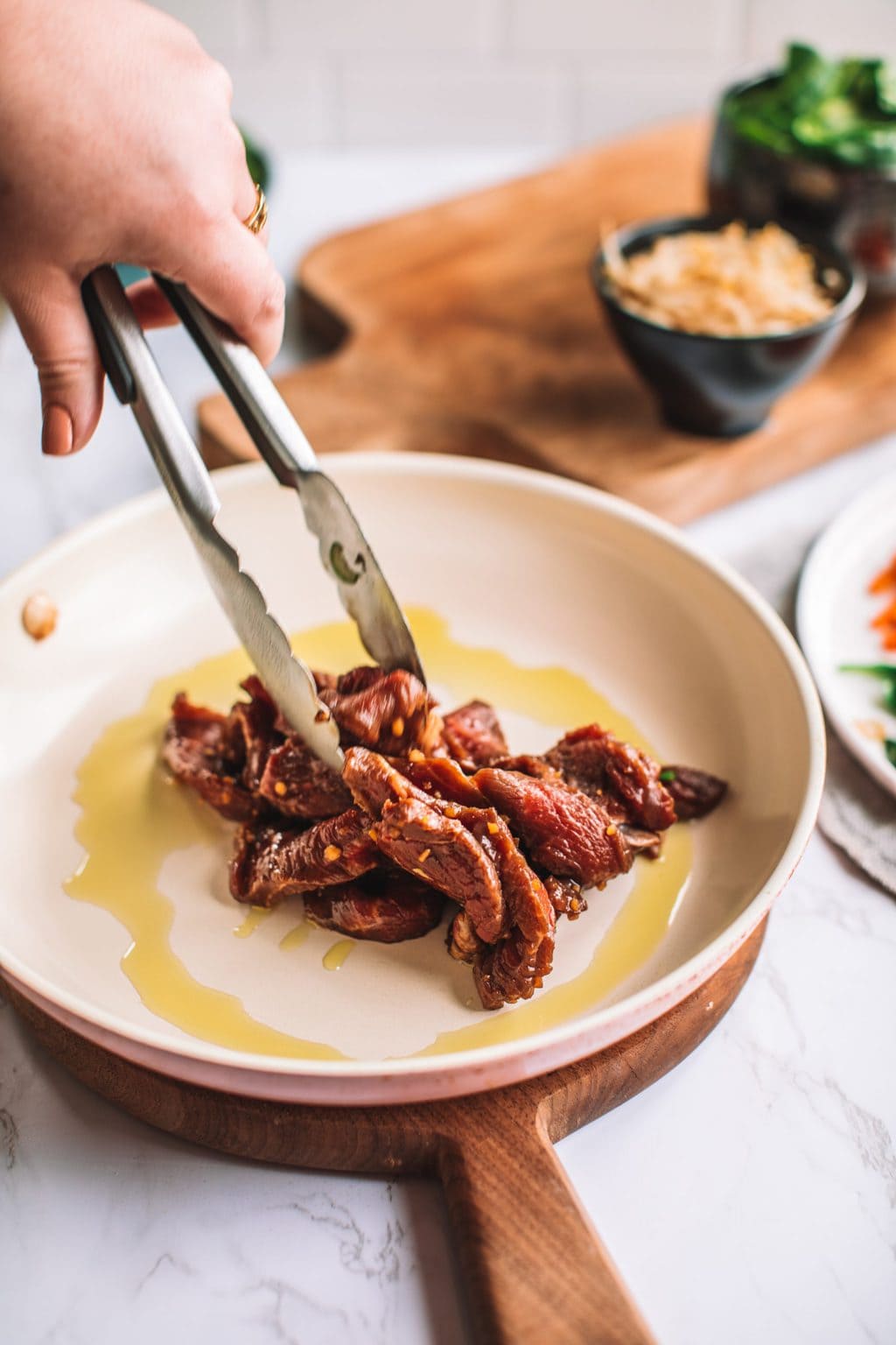 top shot of sliced meat being placed in dish of oil with tongs