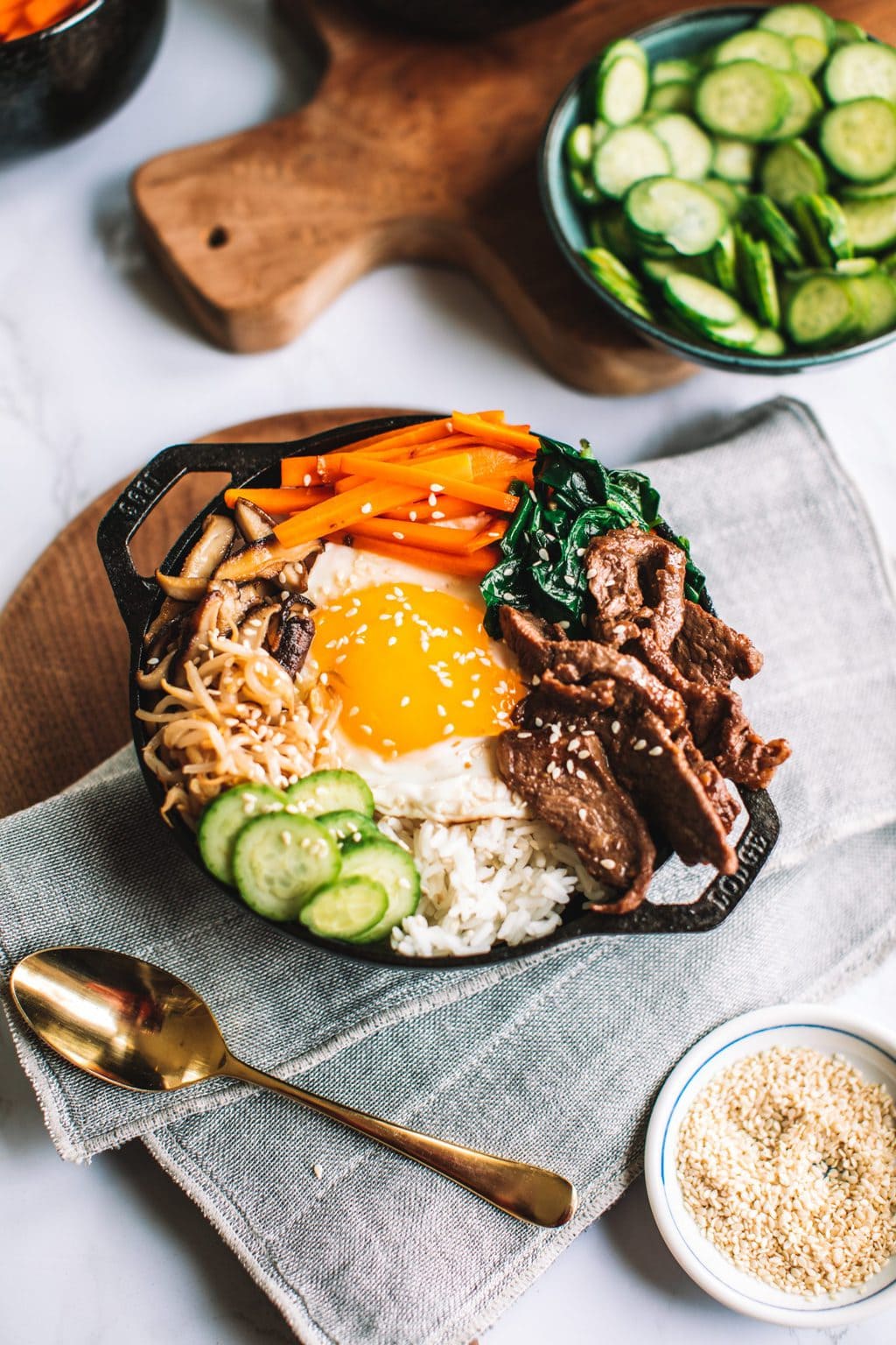 top shot of bibimbap bowl topped with sliced meat, egg, carrots, and other veggies