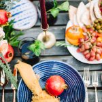 moroccan theme table scape with blue plates, yellow napkins, and a candle set outdoors on a wooden table