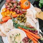 top shot of hummus and fruit platter on wooden table outdoors for moroccan night party