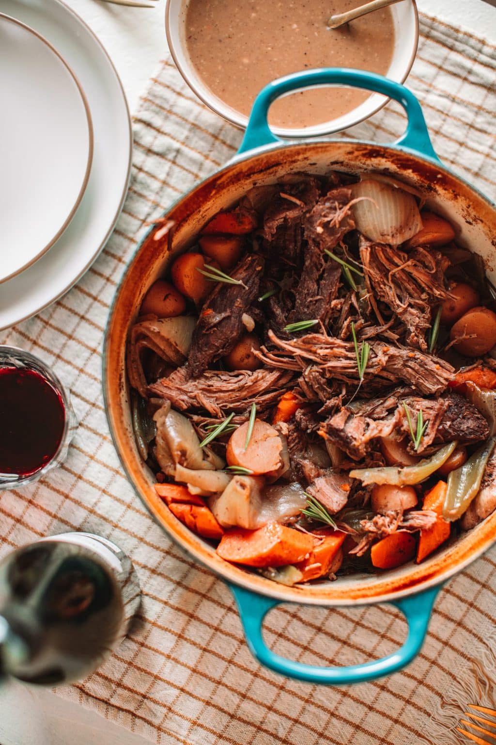 top shot of pot roast and vegetables in dutch oven pot with blue handles