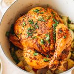 Top shot of cooked whole chicken garnished with parsley in large pot.