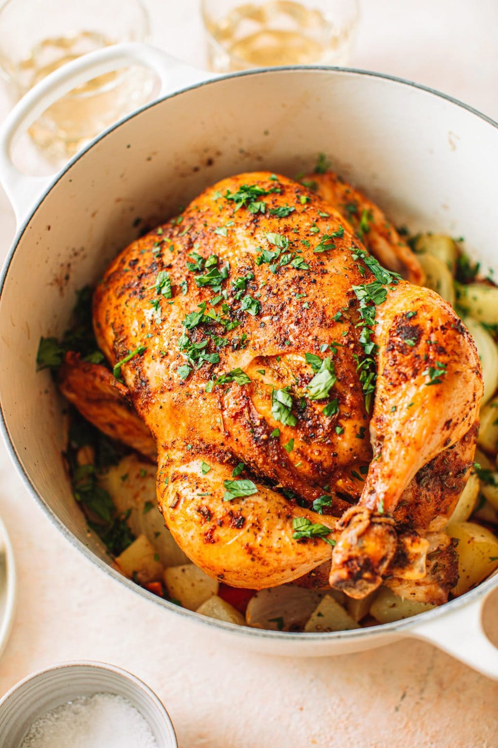 Top shot of cooked whole chicken garnished with parsley in large pot.