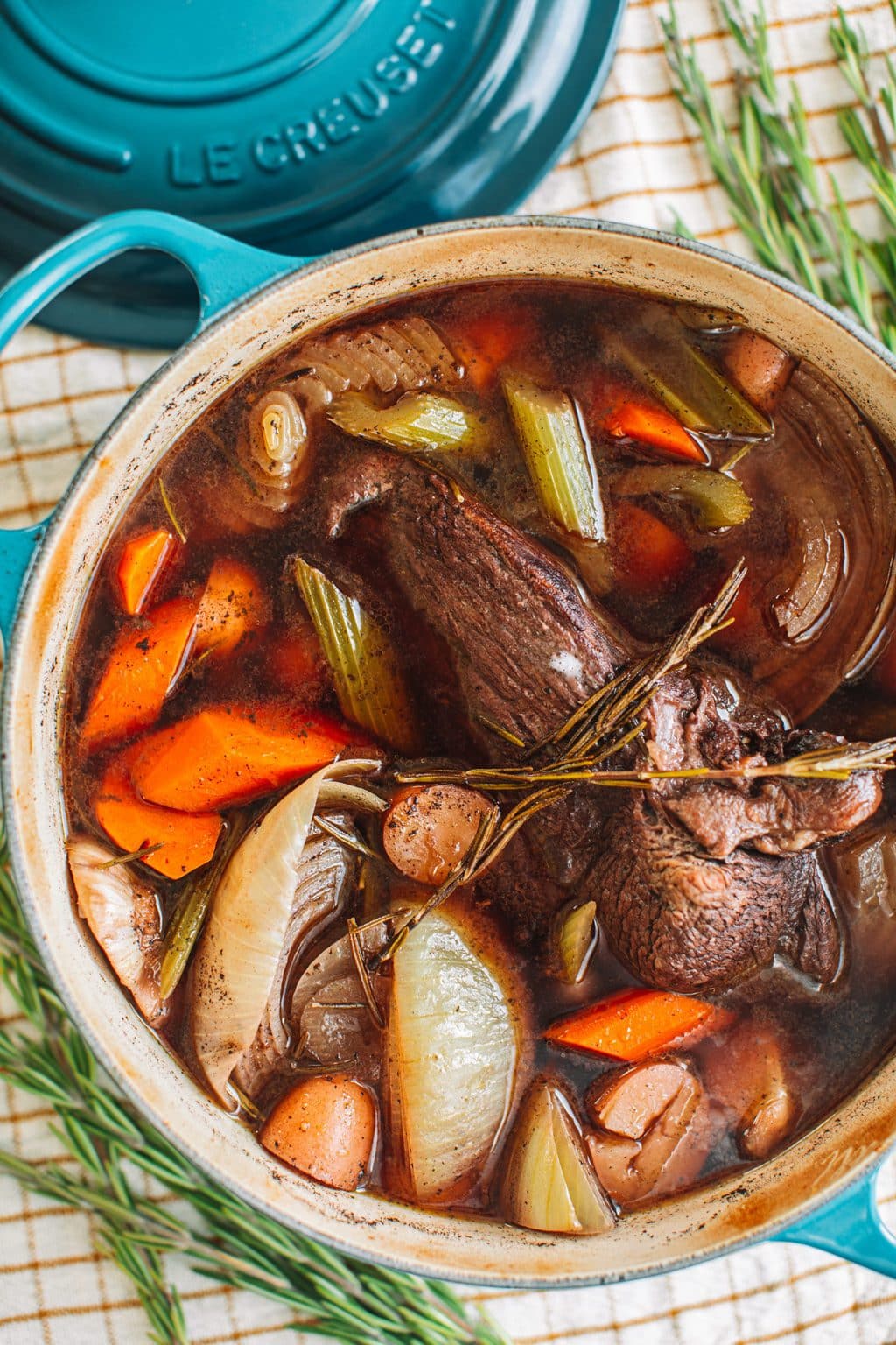 top shot of pot roast and vegetables in dutch oven pot with blue handles