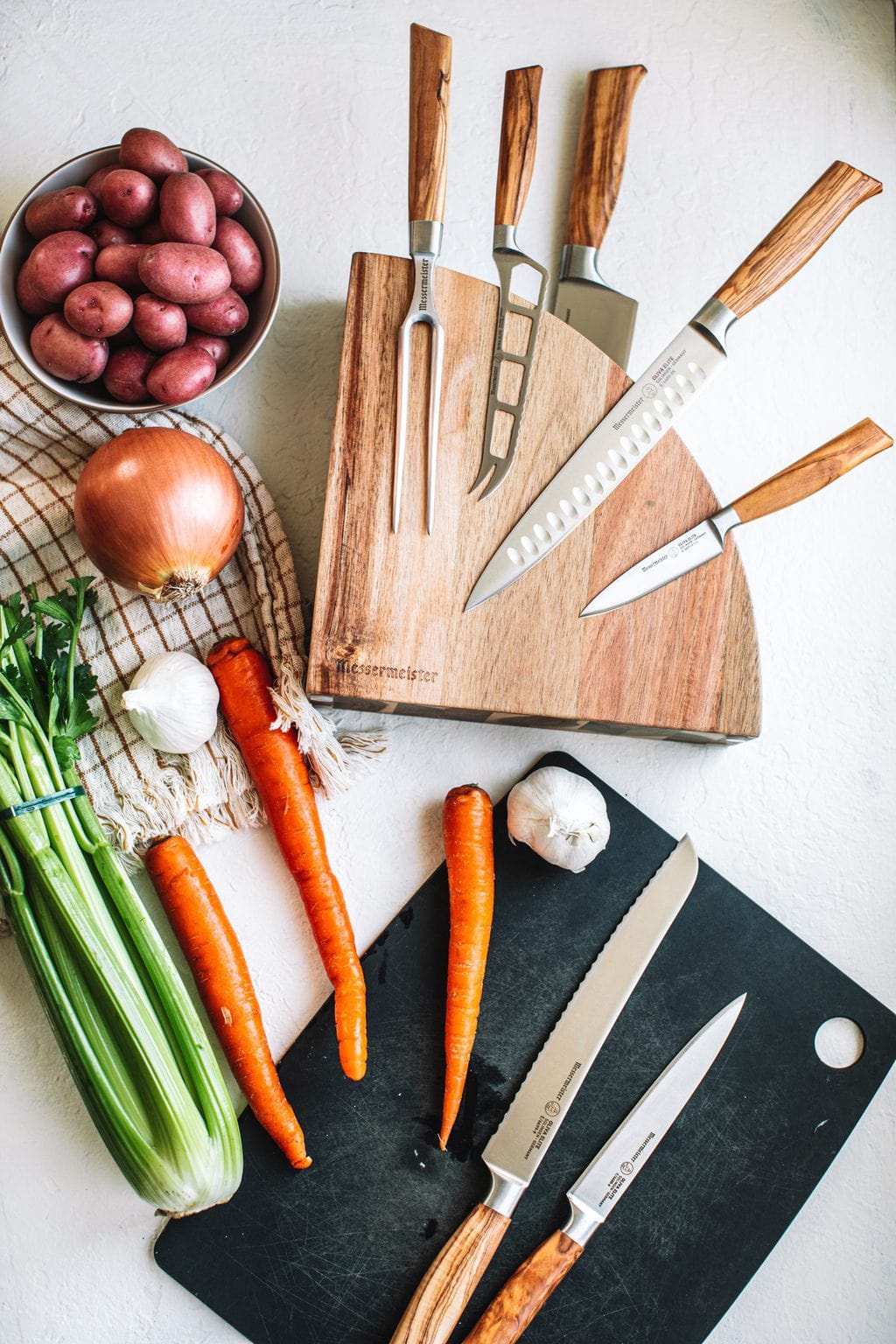 top shot of pot roast ingredients and cooking knives on white countertop