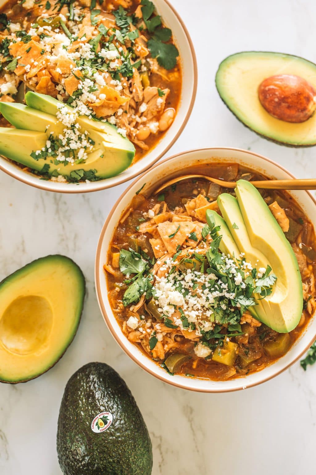 Bowls of chicken enchilada soup with sliced avocado. 