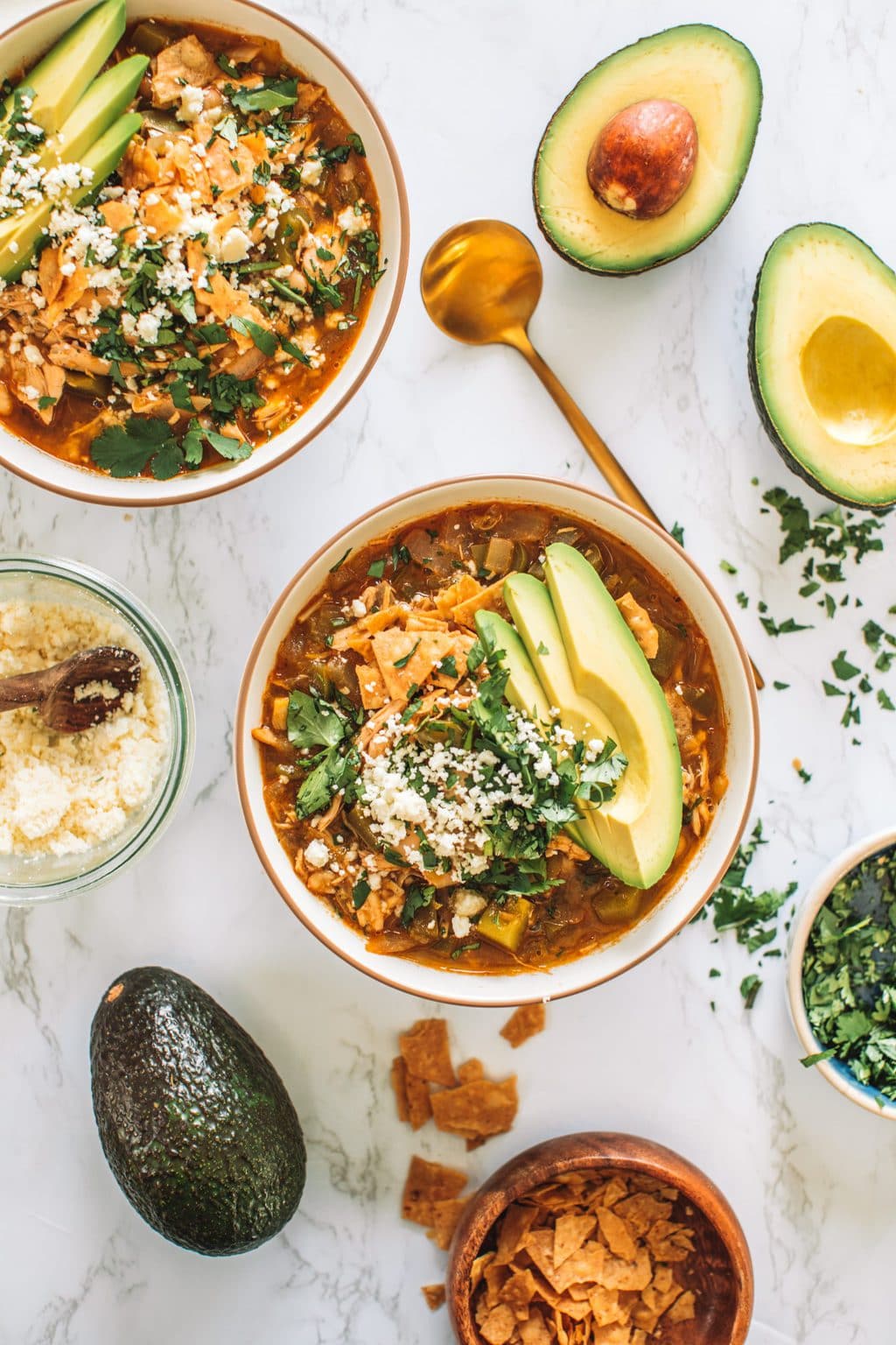 Bowls of chicken enchilada soup with bowls of toppings. 