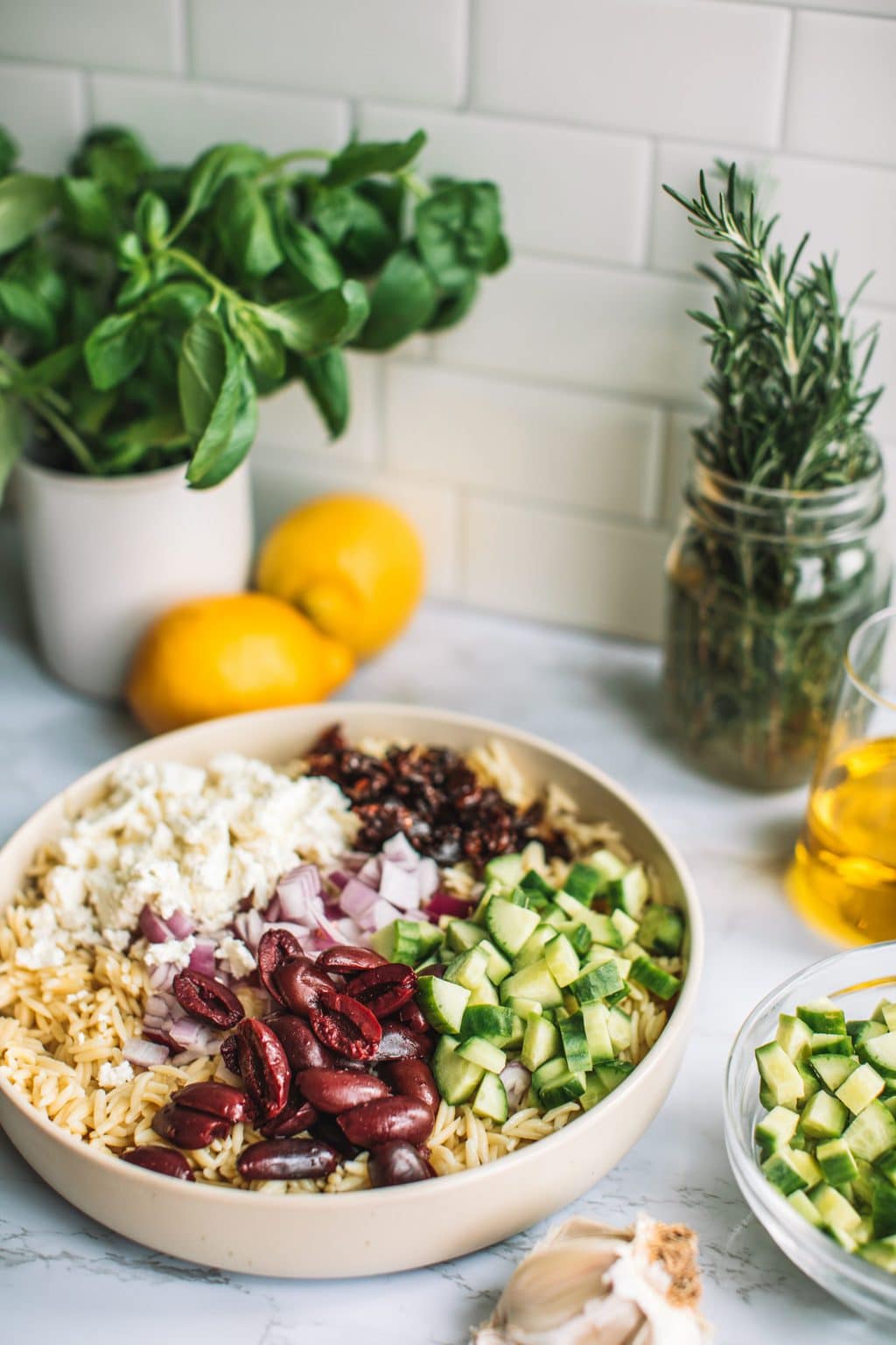 Top shot of ingredients sectioned on top of pasta dish, including feta cheese, olives, and chopped veggies.