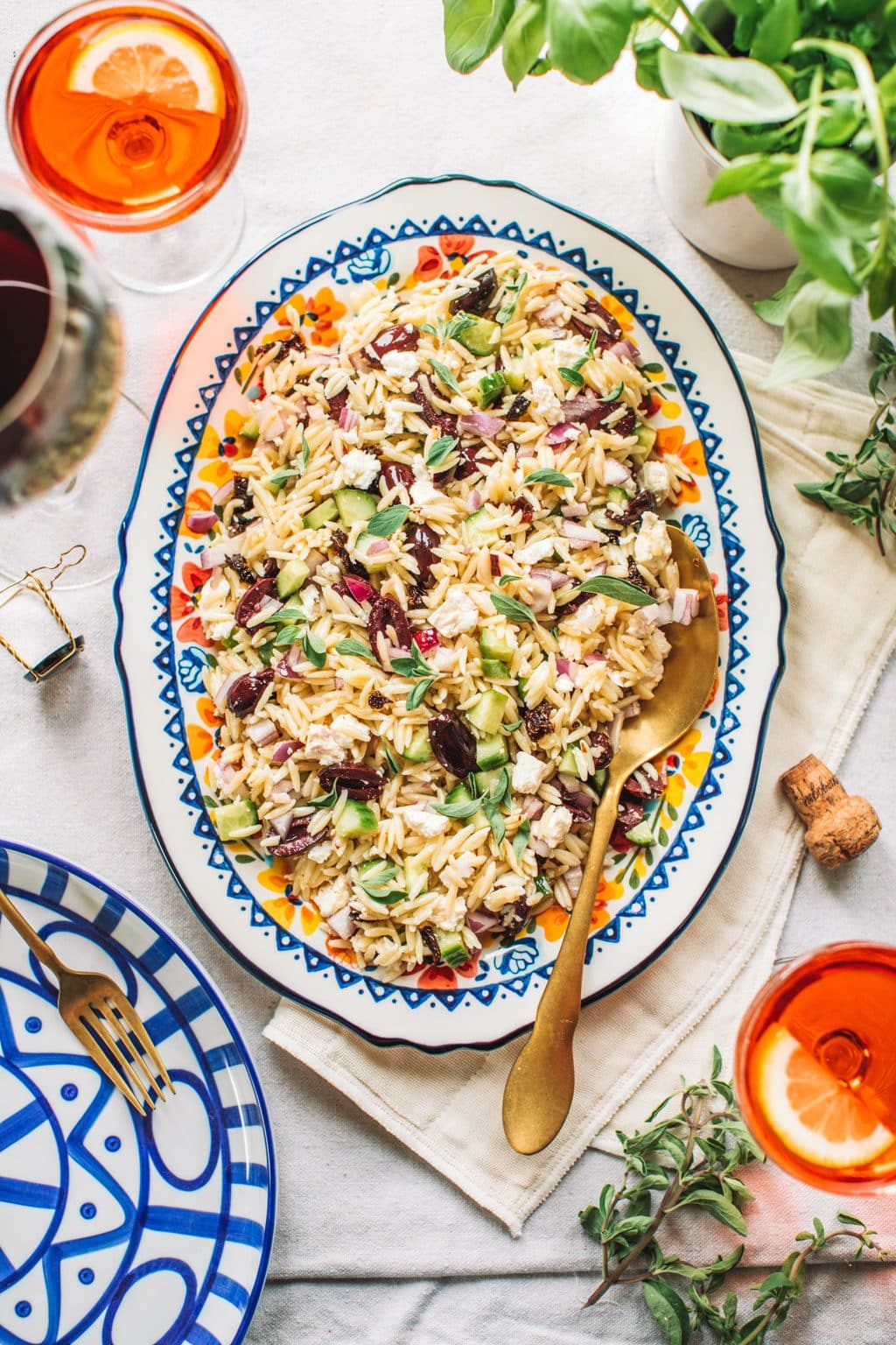 Top shot of orzo lemon salad with gold spoon on large oval serving dish.