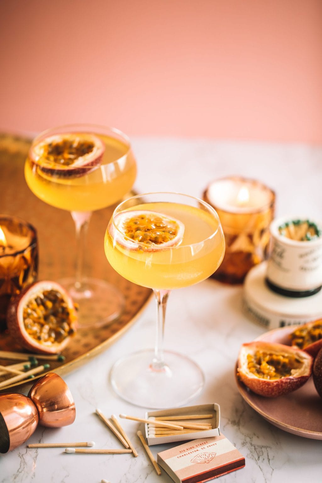 A passion fruit martini served in a coupe glass and a garnished with a passion fruit half.