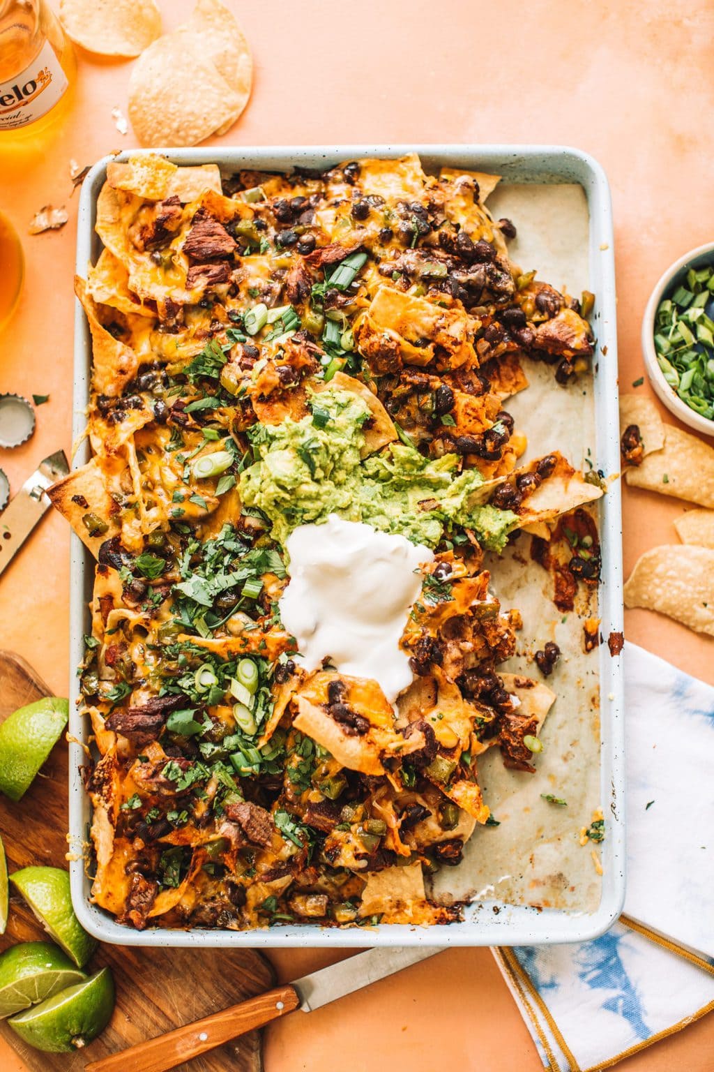 A platter of steak nachos with some scooped off and eaten. 